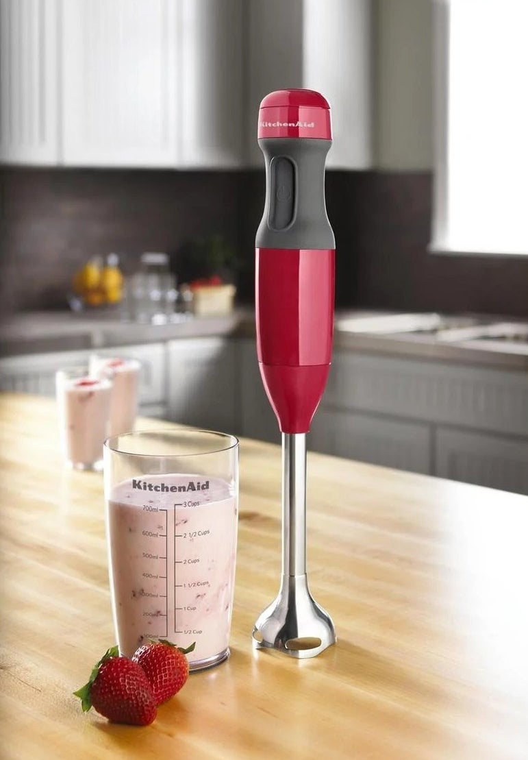 silver immersion blender next to cup filled with strawberry smoothie
