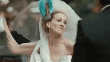 A GIF from the Sex and the City movie - Carrie wears a wedding dress and is hitting Big over the head with her bouquet