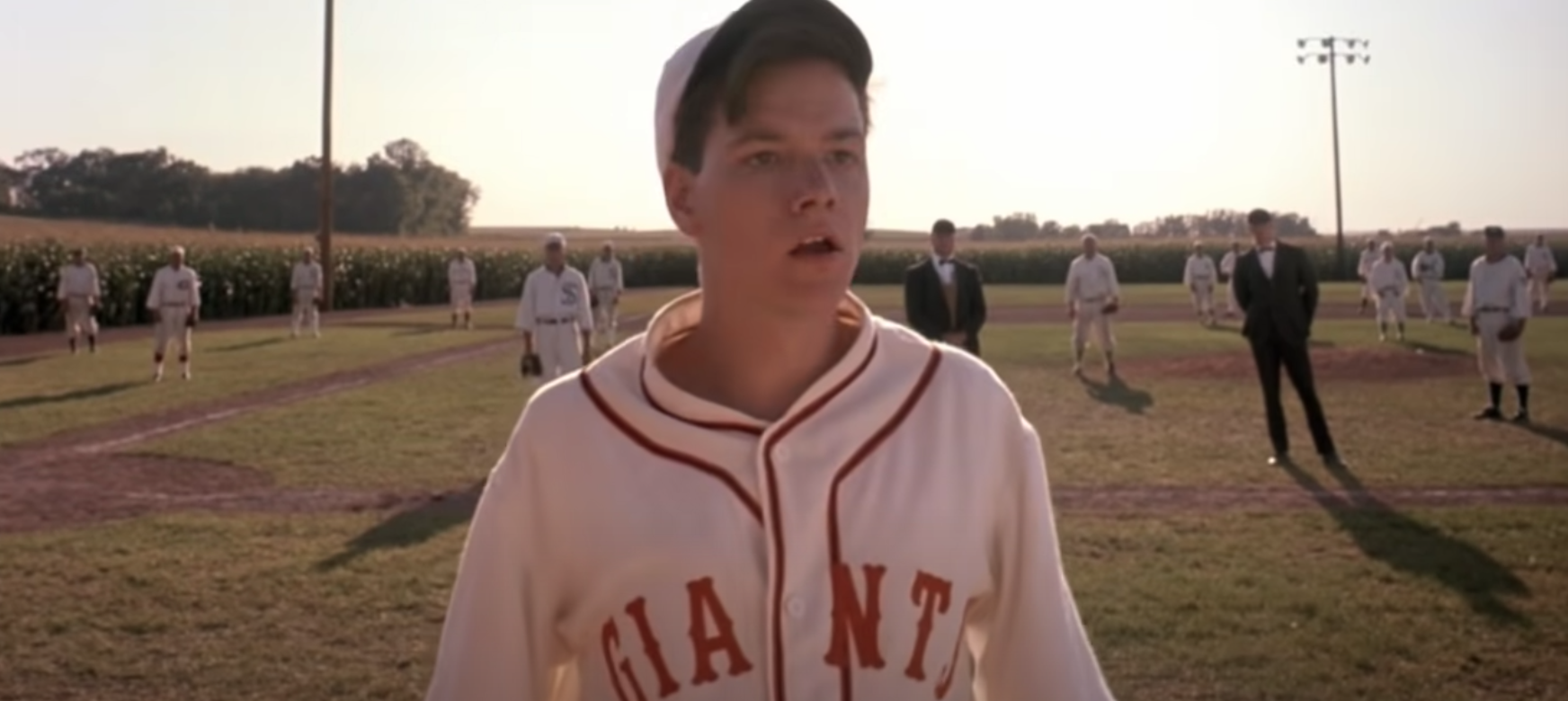 A man in a baseball uniform stands in a field