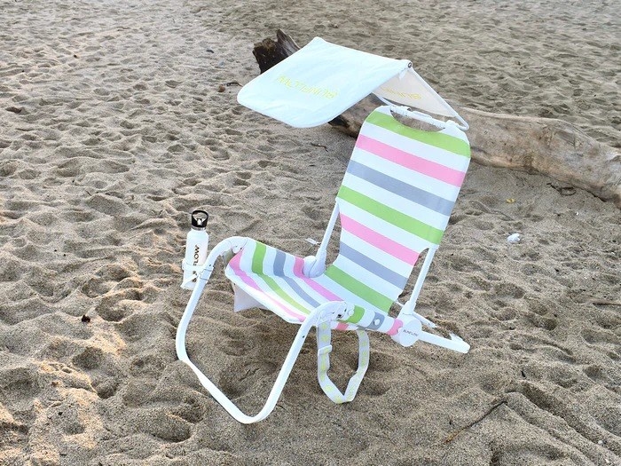 a striped beach chair with a hanging shade over it
