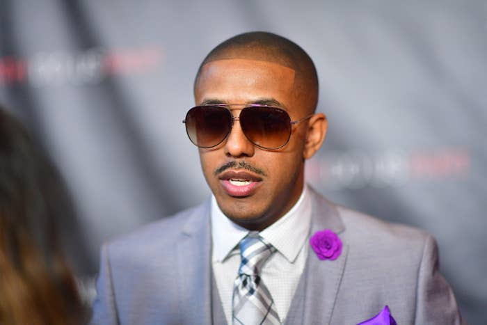 A close-up of Marques wearing a suit, tie, and aviator sunglasses