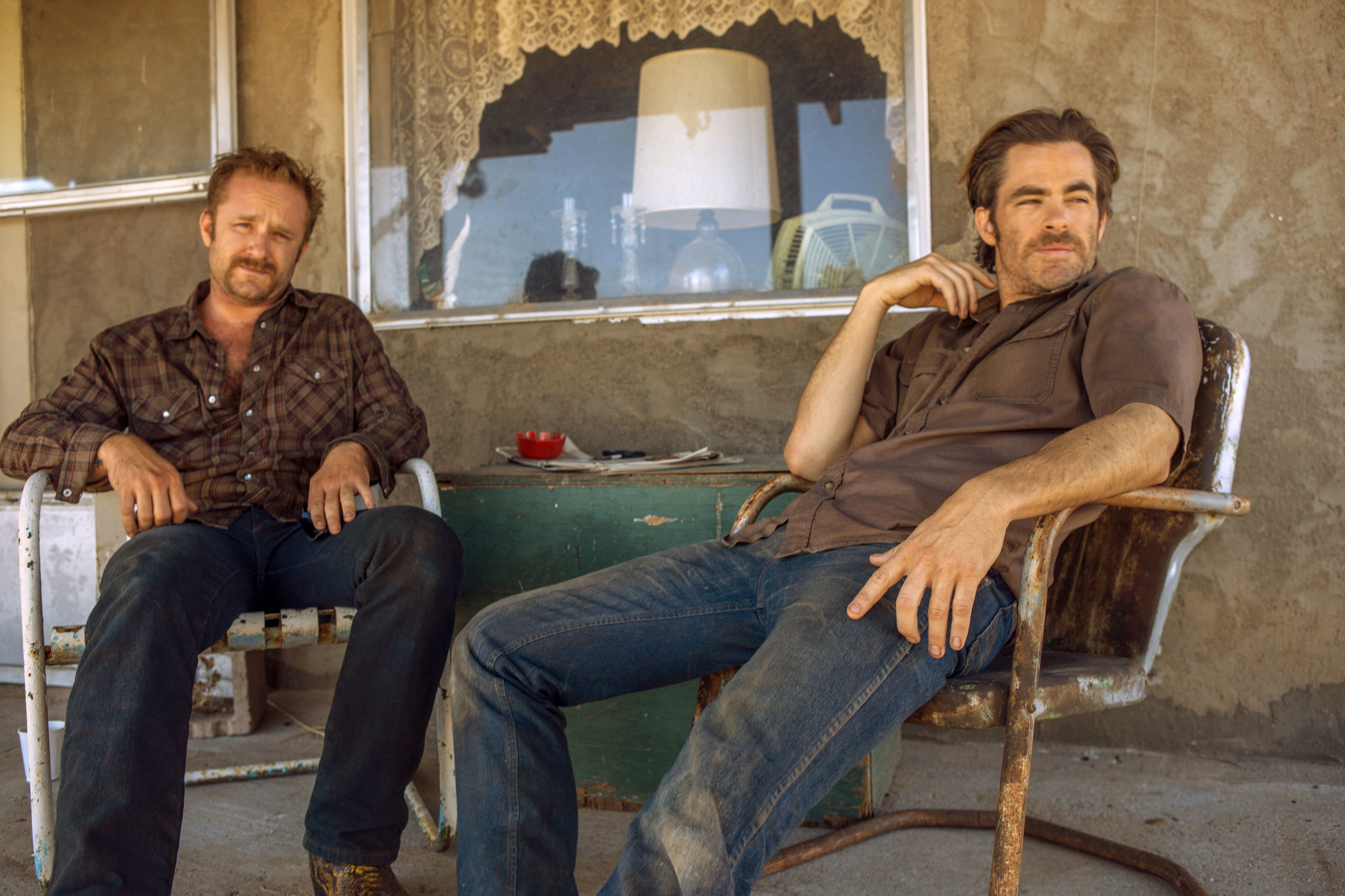 Ben Foster and Chris Pine lounge in a beat up metal porch chairs in Hell of High Water