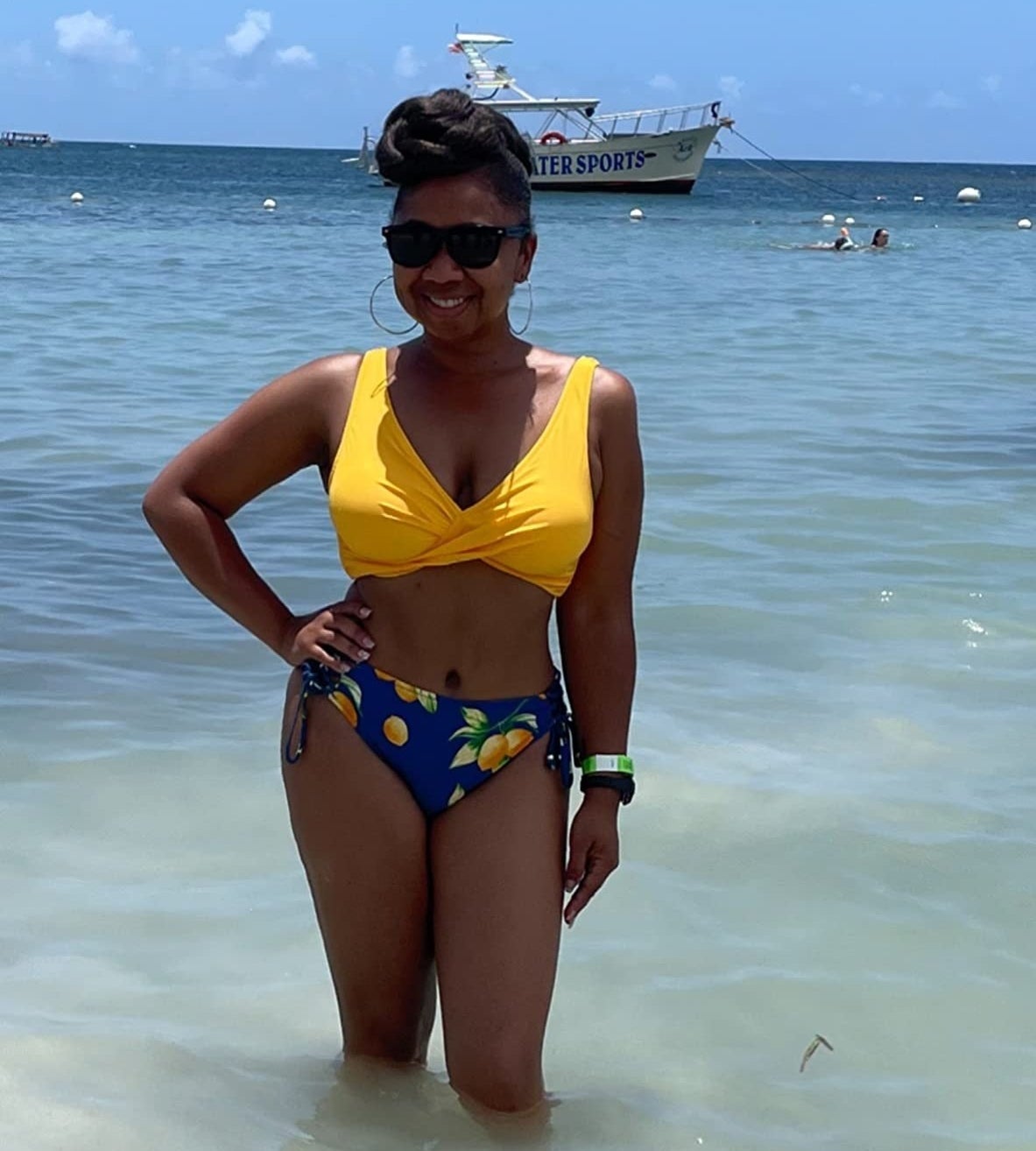 a reviewer wearing the yellow and blue floral swimsuit at the beach