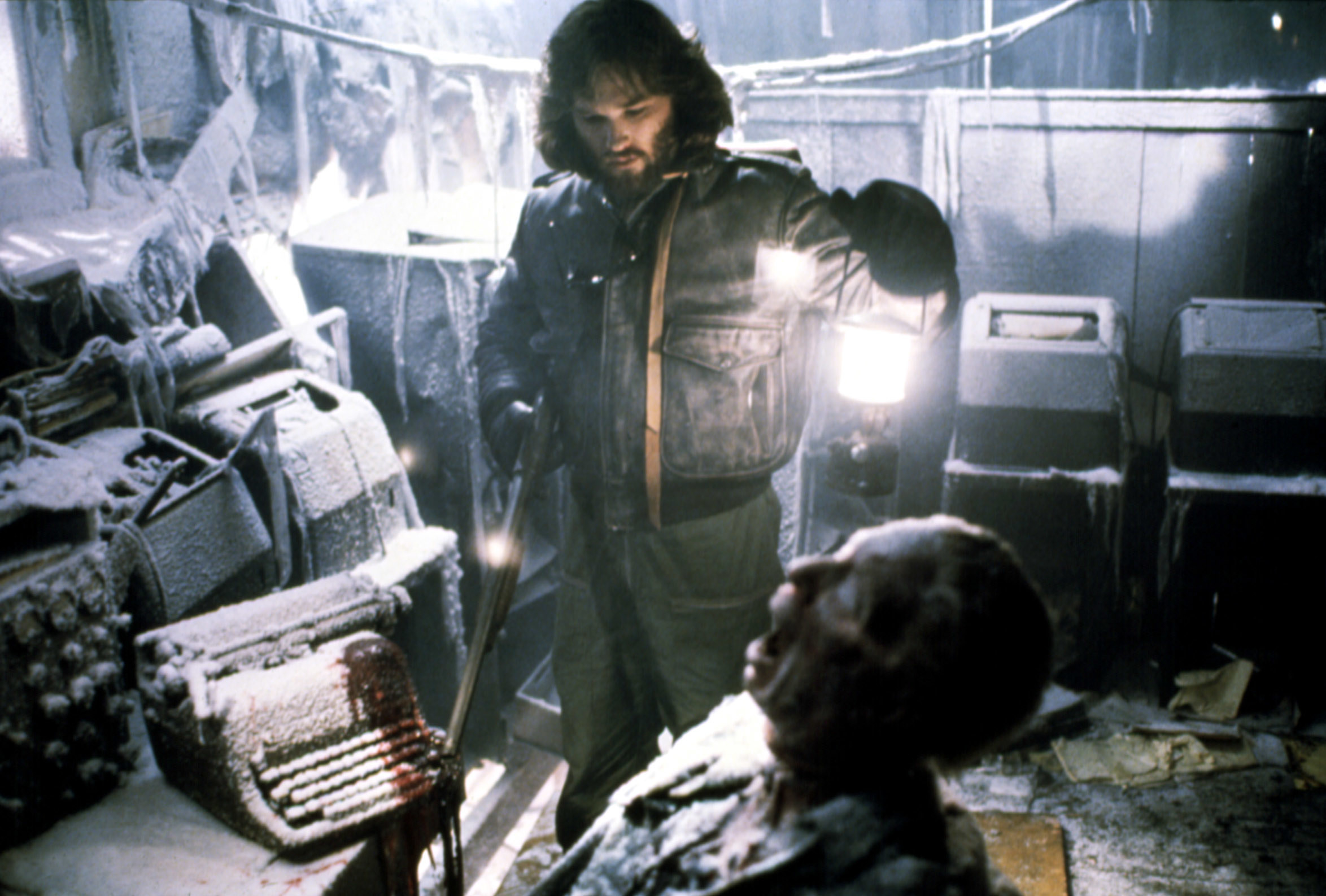 Kurt Russell examines a corpse in a frozen outpost