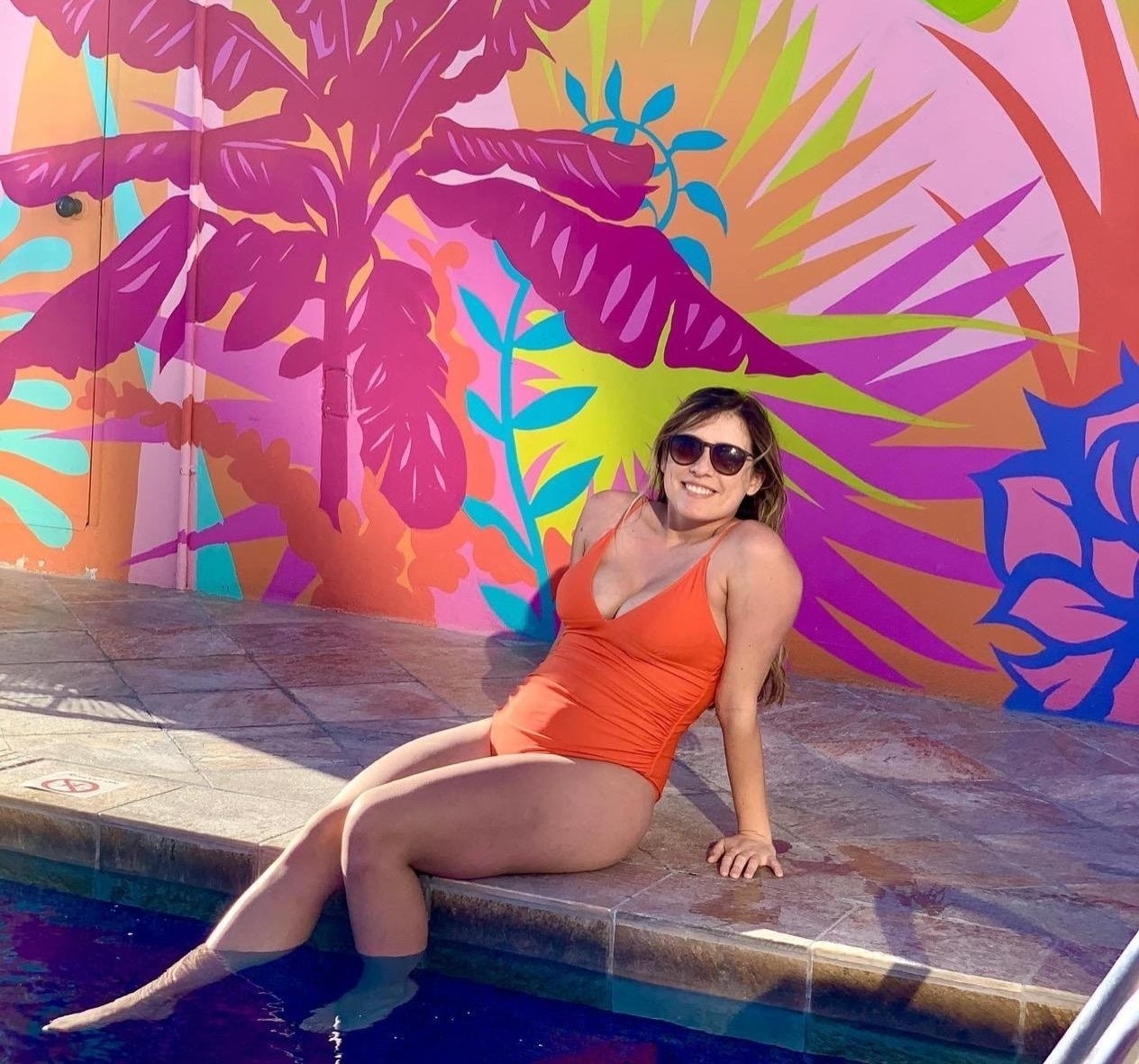 a reviewer wearing the orange swimsuit at a pool