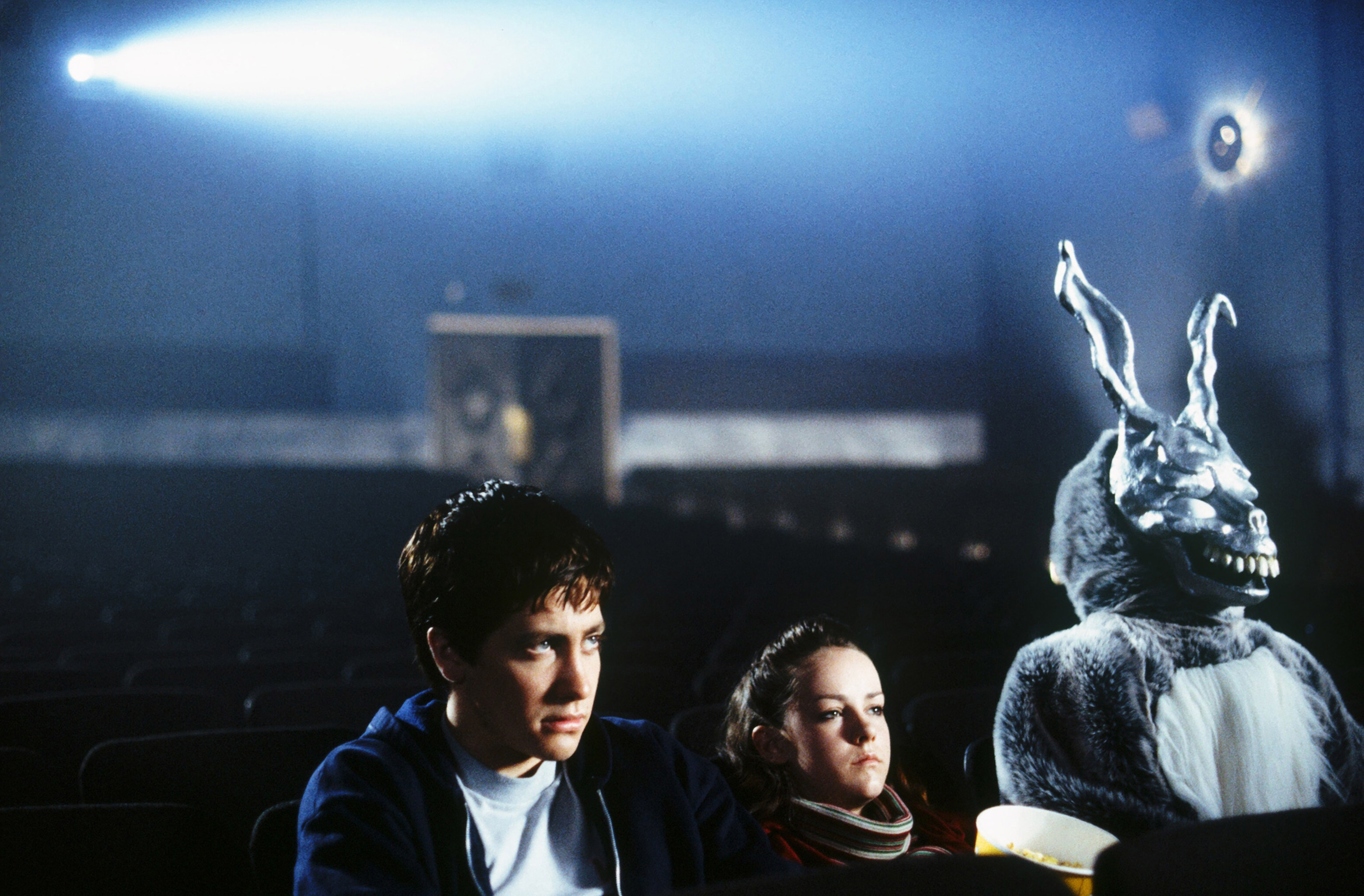 Jake Gyllenhaal, Jena Malone, and the monstrous killer rabbit Donnie Darko watch a movie in a dark theater