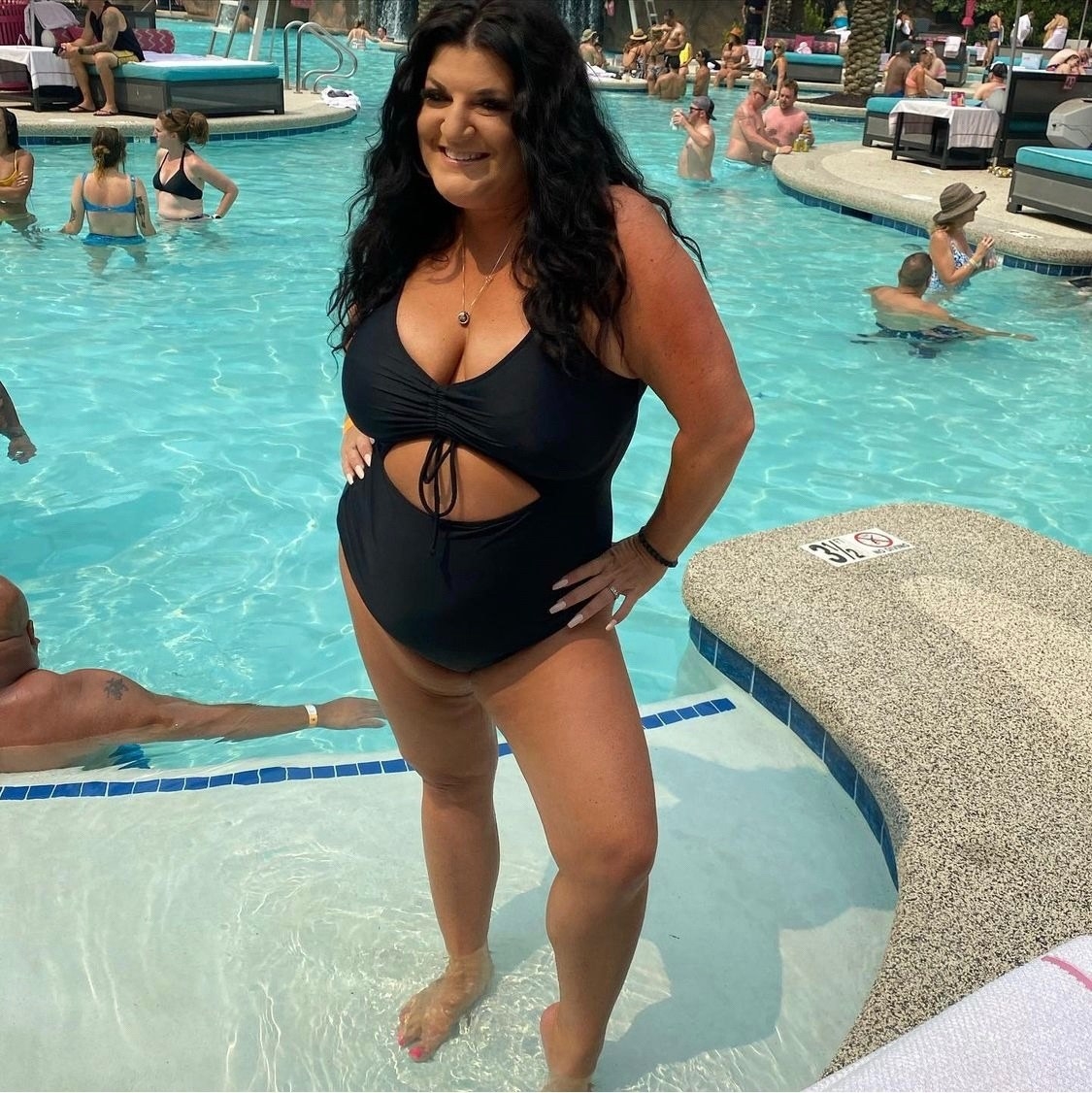 a reviewer wearing the black swimsuit at the pool