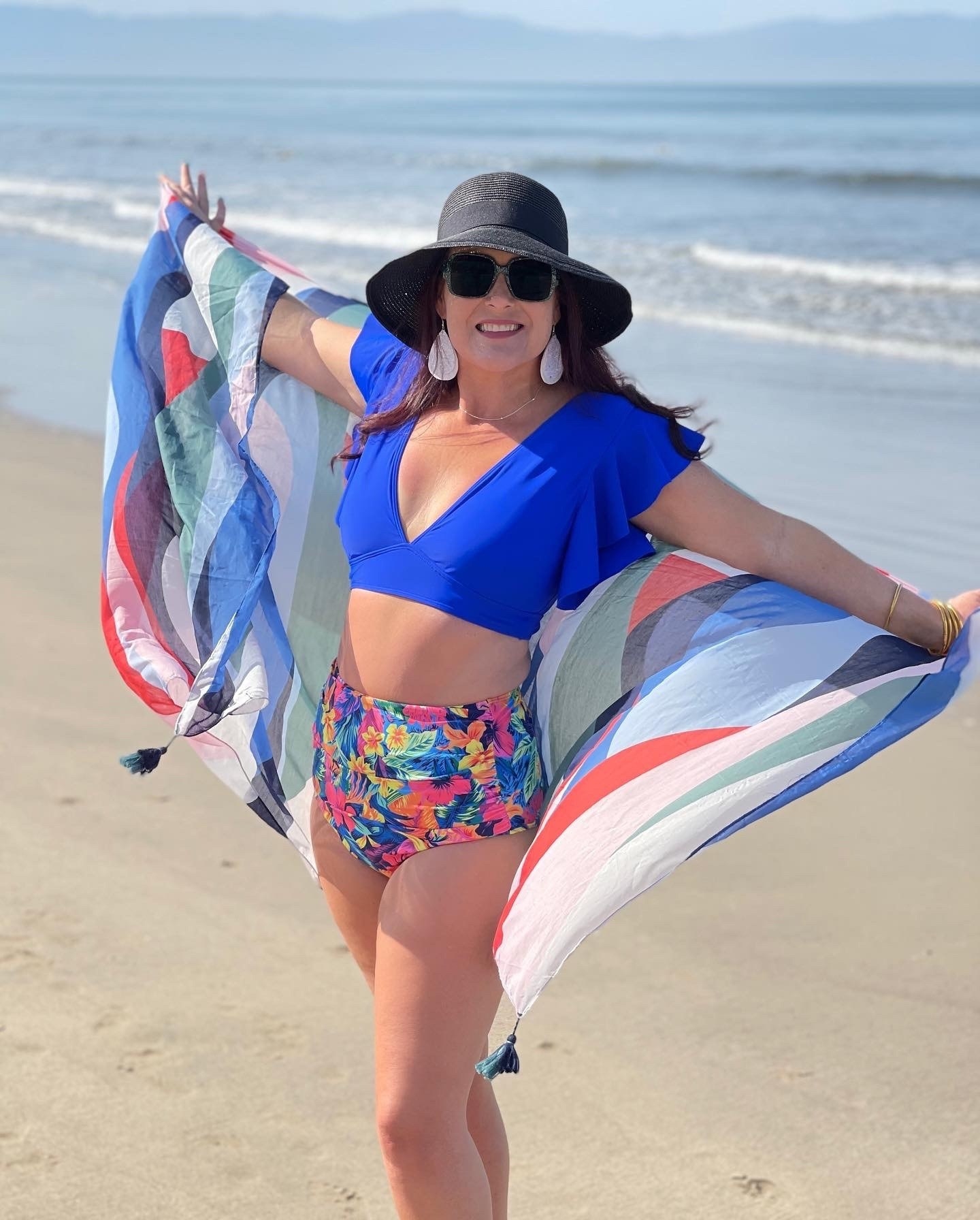 a reviewer wearing the blue top with floral bottoms on the beach
