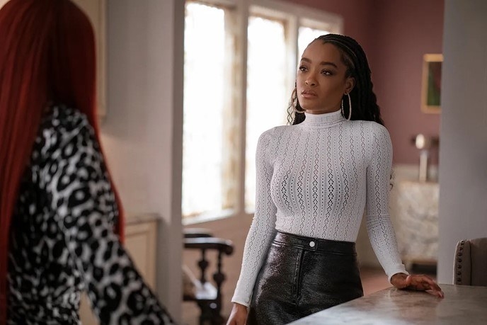 LaToya Tonodeo as Diana in a knit, long-sleeved turtleneck top standing in front of another woman