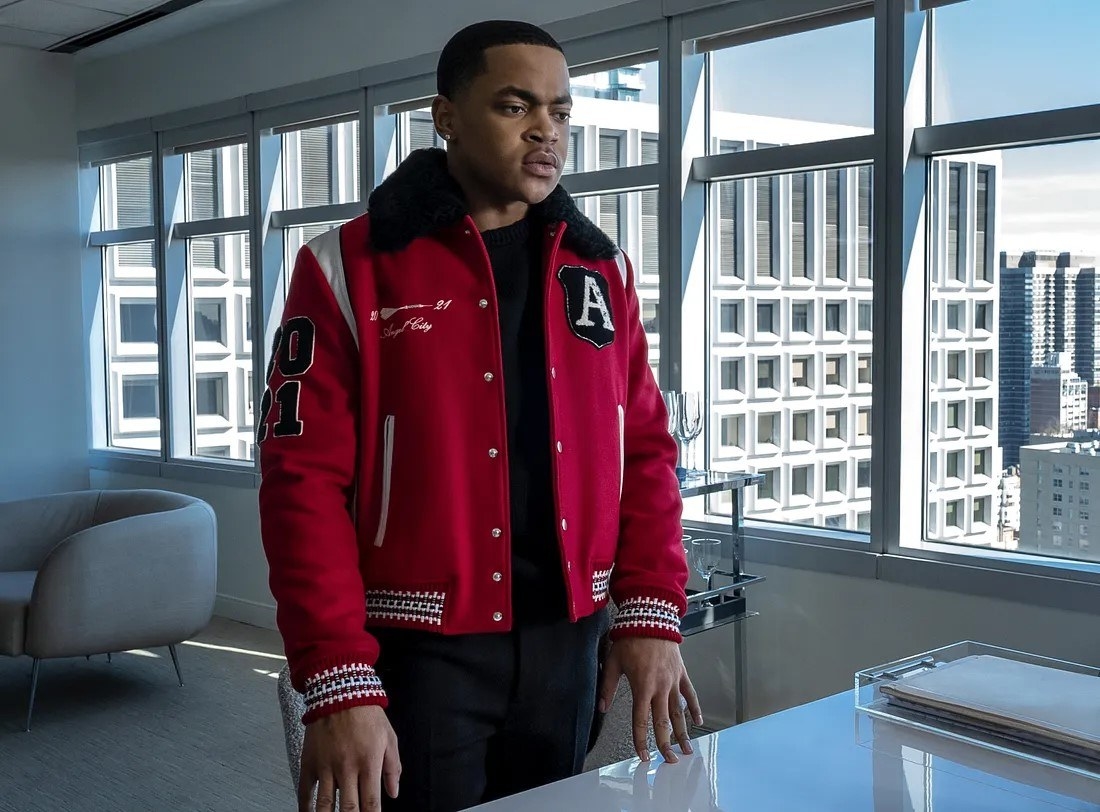 Tariq in a varsity jacket standing in front of a desk