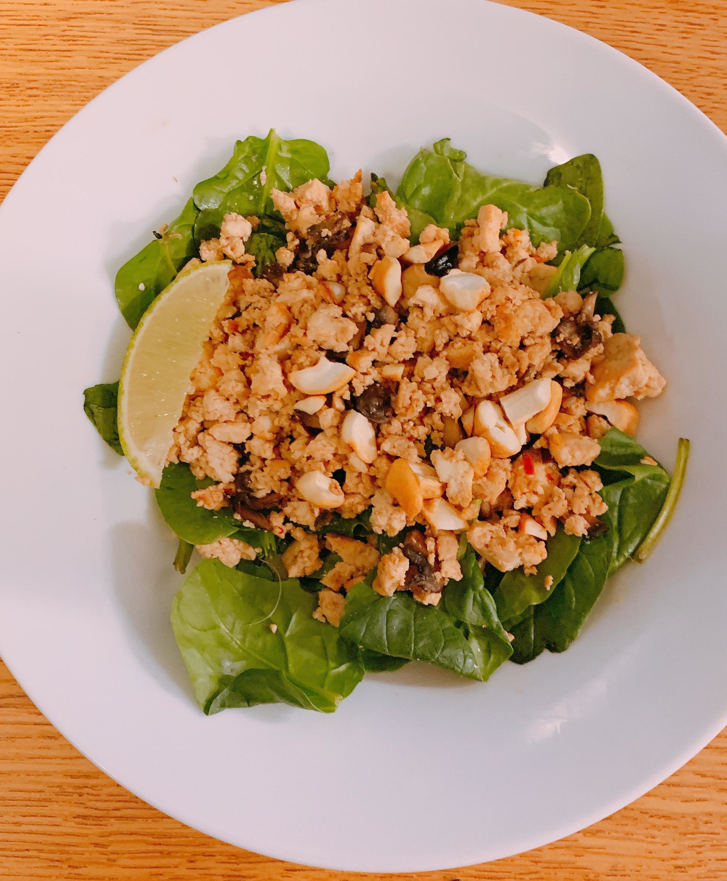 lettuce wraps filled with crumbled tofu and peanut mixture, with lime wedges for squeezing