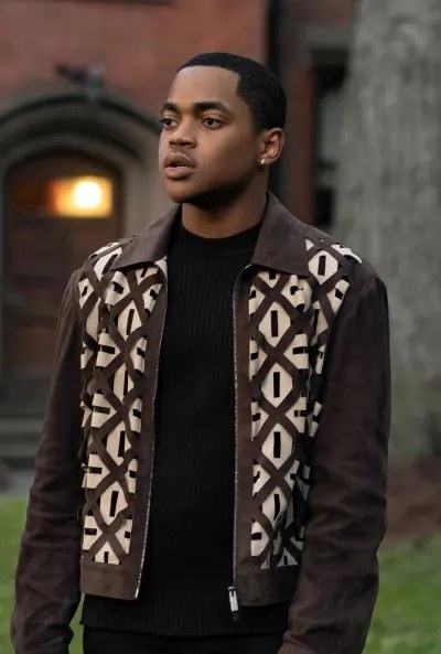 Tariq in a short, zip-front jacket, standing on campus