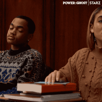 Tariq and Paige, both wearing sweaters, sitting at a desk and smiling