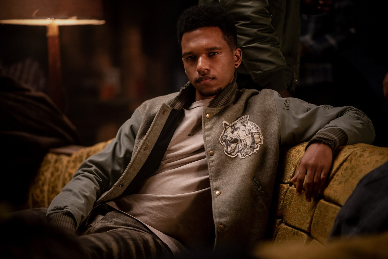 Dru Tejada sitting on a couch wearing a jacket and T-shirt