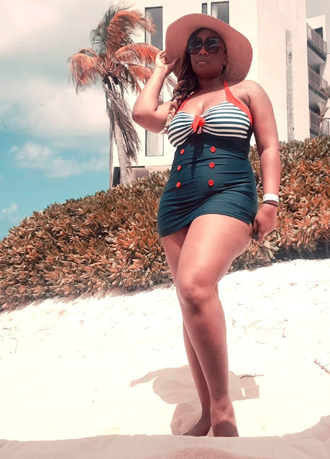 a reviewer wearing the blue, red and striped swimsuit at the beach