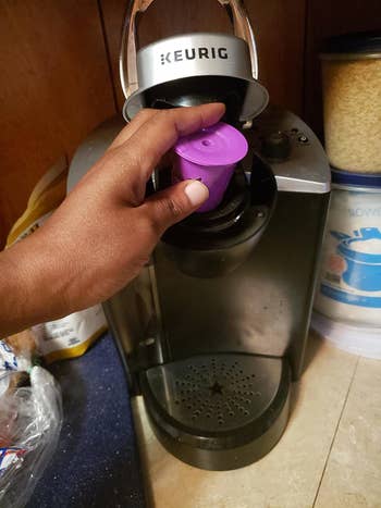 Reviewer placing their reusable K-cup into their Keurig coffee machine