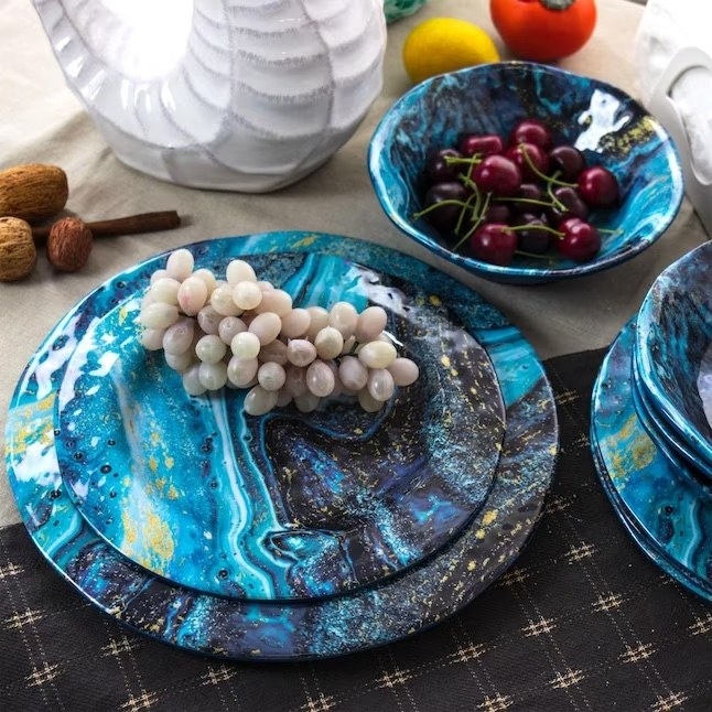 eight blue plates with a mesmerizing swirl holding fake grapes and cherries