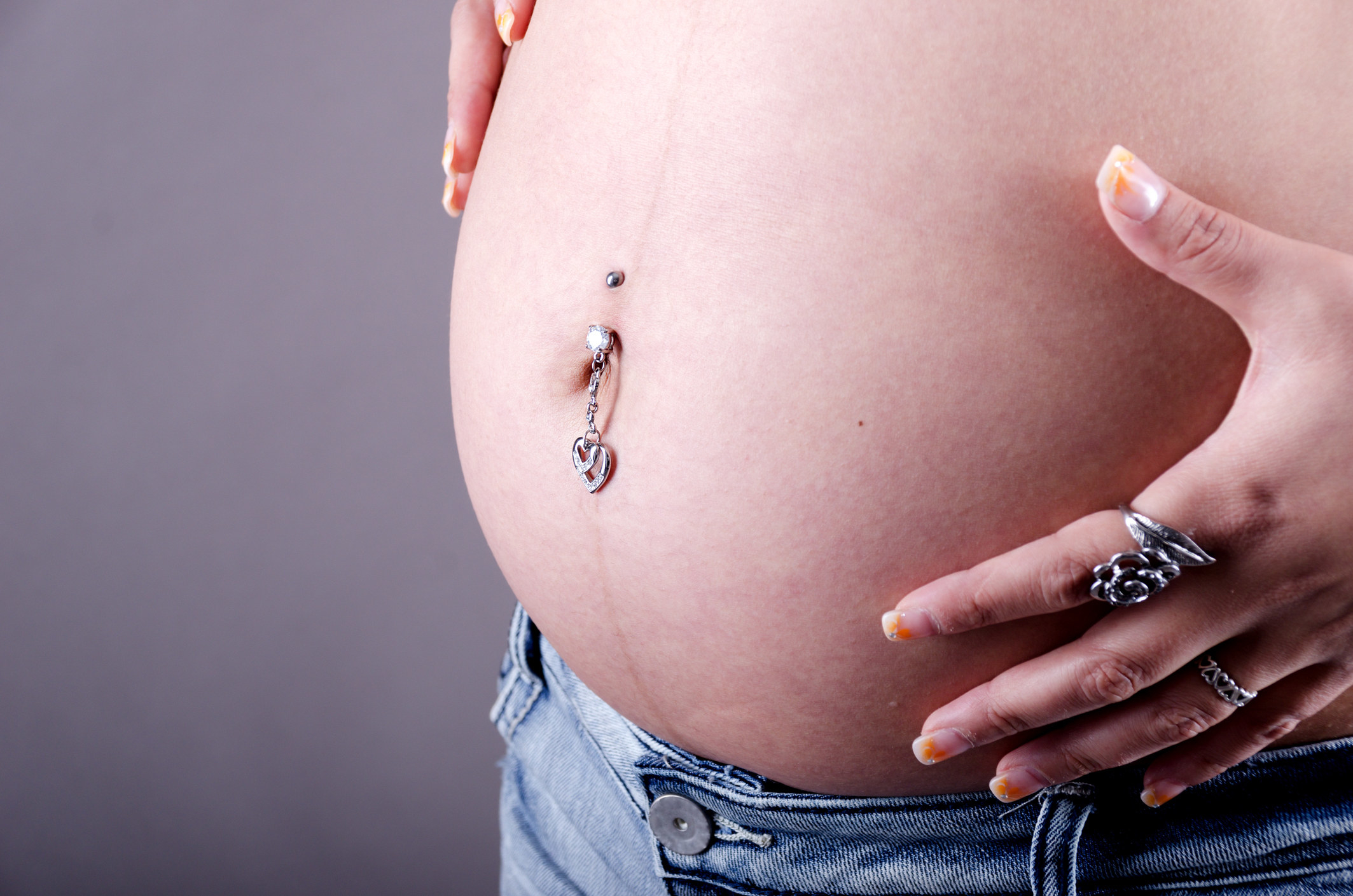 A pierced belly button on a pregnant woman
