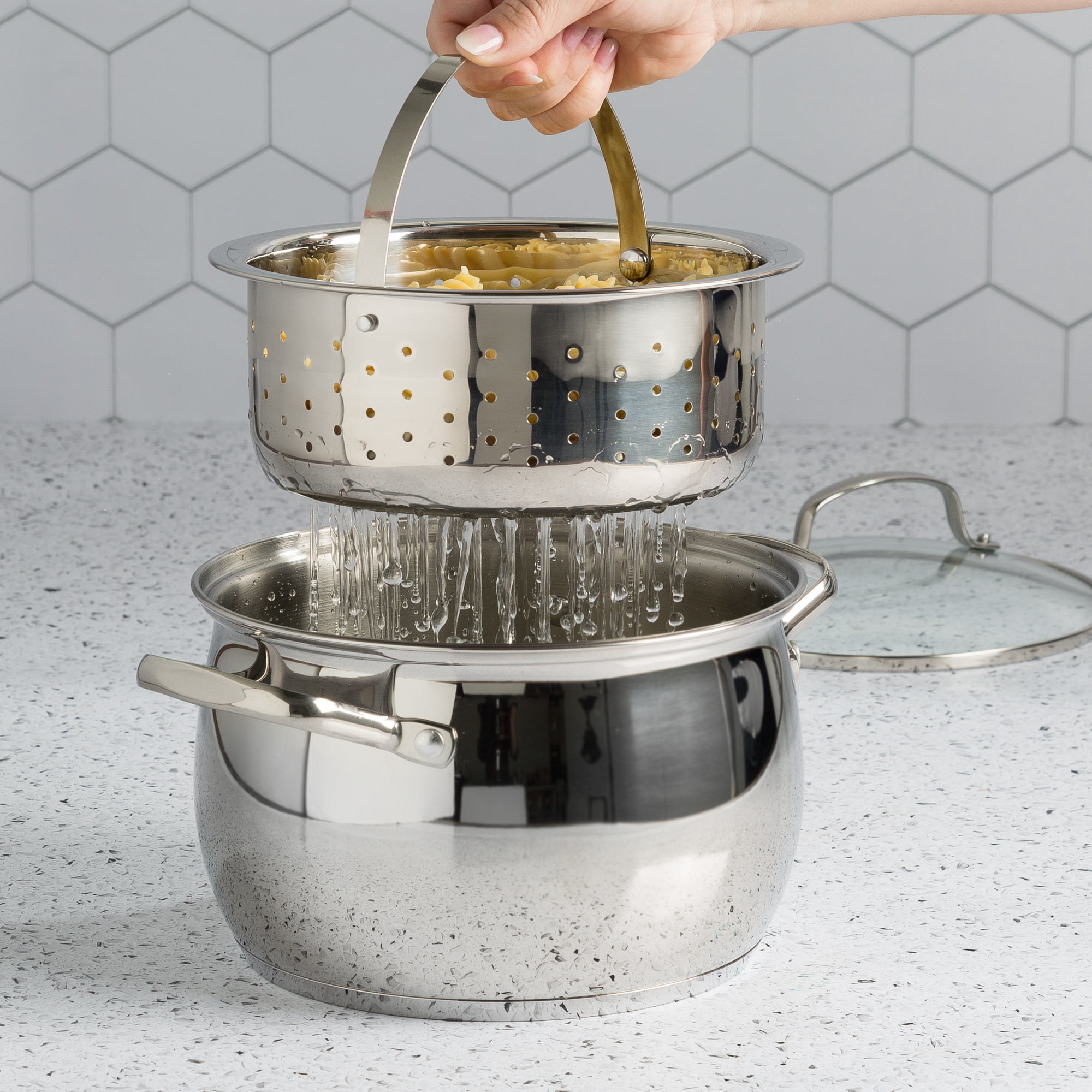 stainless steel pot draining pasta in its included colander and its lid on the counter