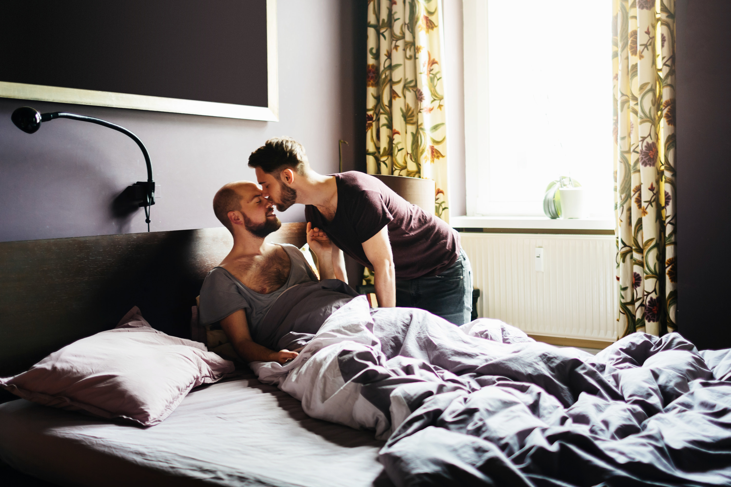 A partner kissing their partner on the nose in bed