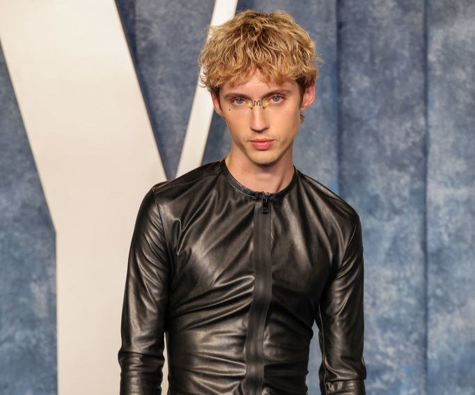 Troye in a leather-looking, long-sleeved zipper-front top
