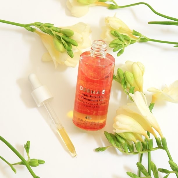 A bottle of facial oil with a dropper and flowers