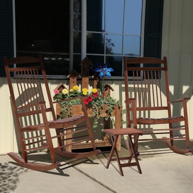 two wooden rocking chairs and a same-colored folding table outside a home