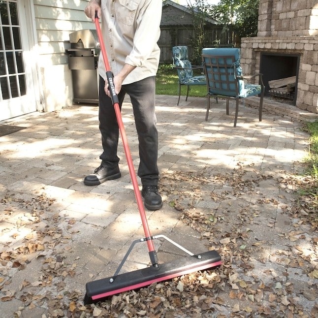 a person cleaning their outside patio with a multi-surface broom