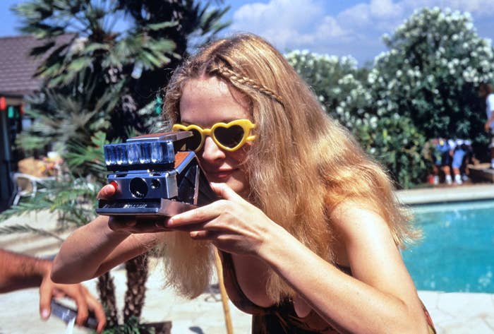 Heather in the movie taking a polaroid picture by the pool