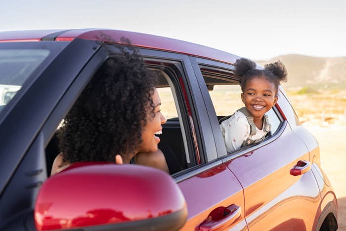 A mother and daughter smiling at each other in their car