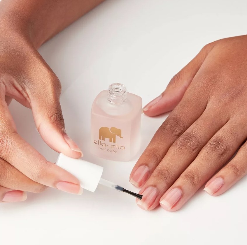 A woman using the nail care polish on her nail beds