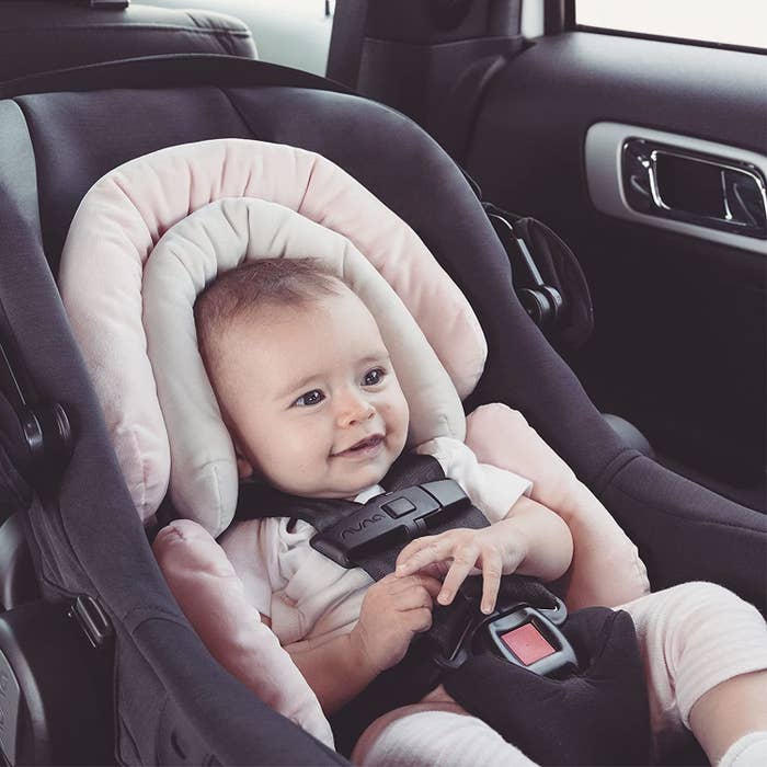 A baby in a car seat on a cushion