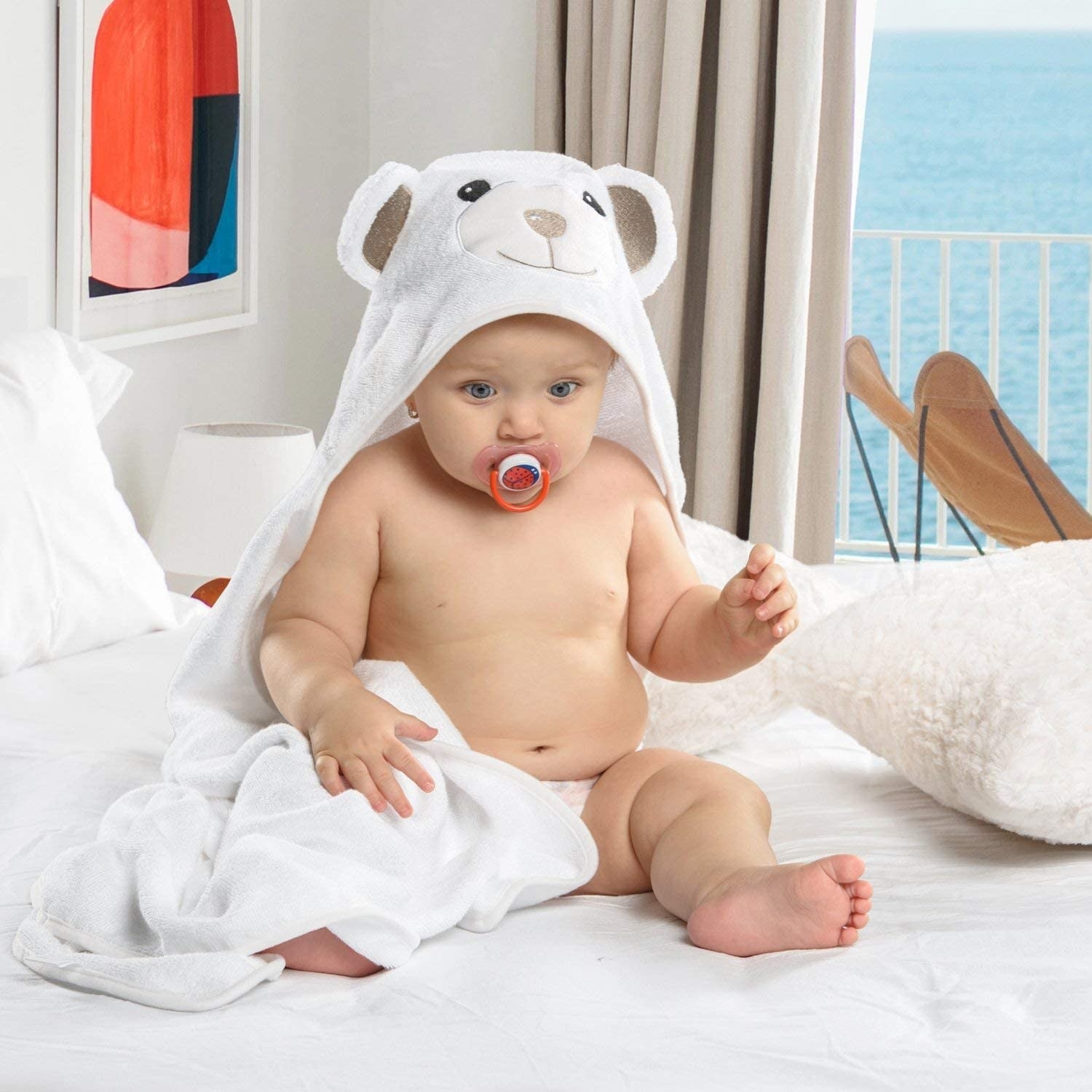A baby on a bed wearing the towel