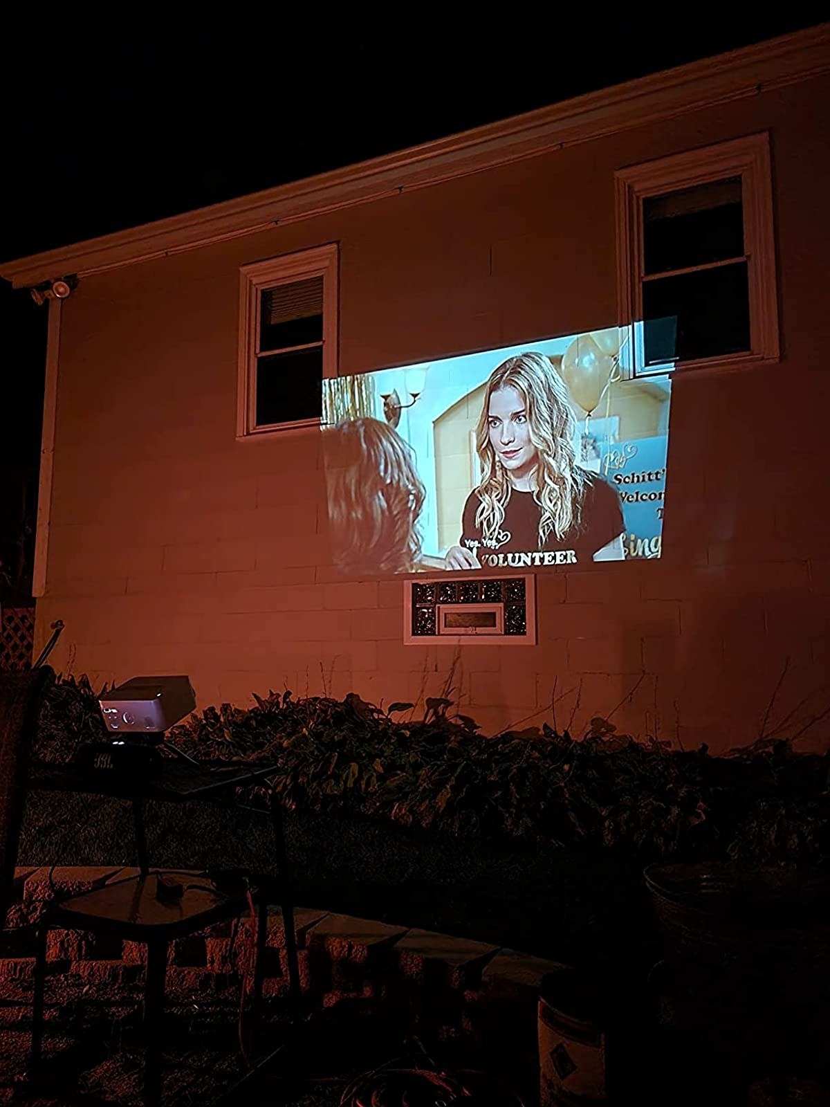 Reviewer streaming Schitt&#x27;s Creek on side of house with projector