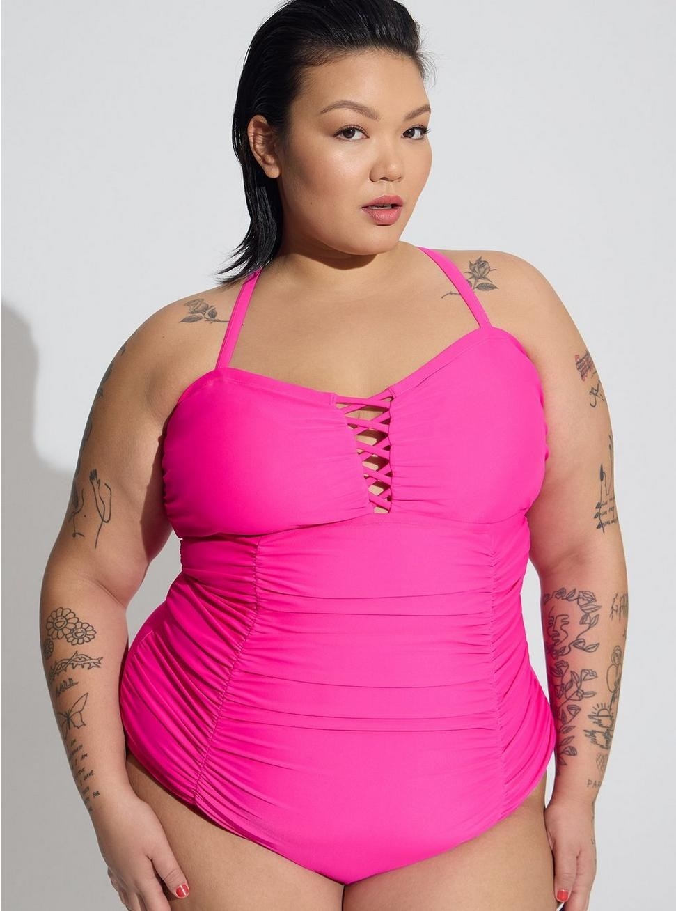 model in hot-pink ruched one-piece bathing suit with a lattice front small cutout