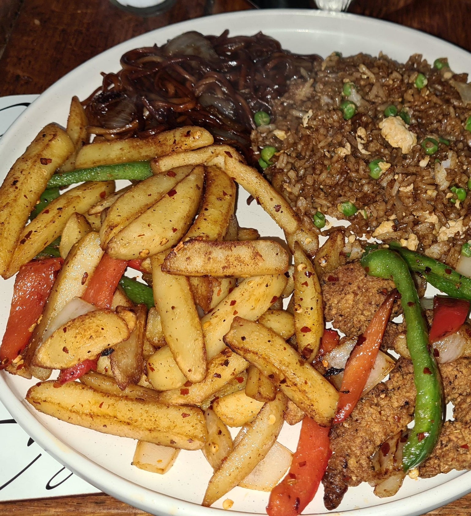 plate of chinese food with fries seasoned with spices, onions, and bell peppers