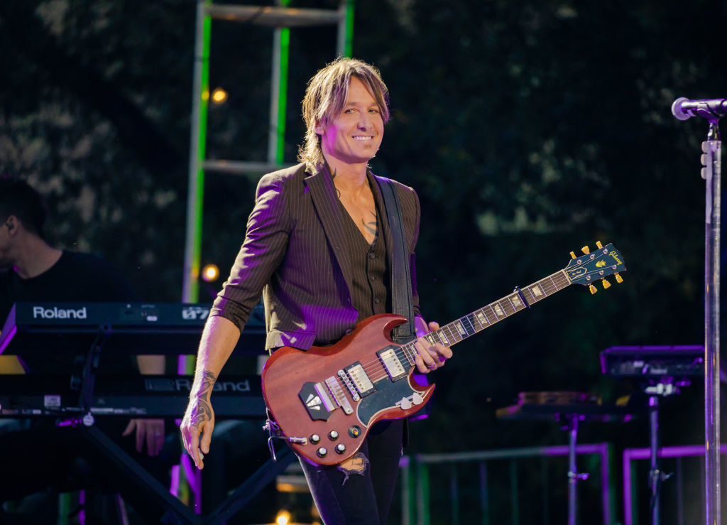 Keith Urban smiling and holding a guitar