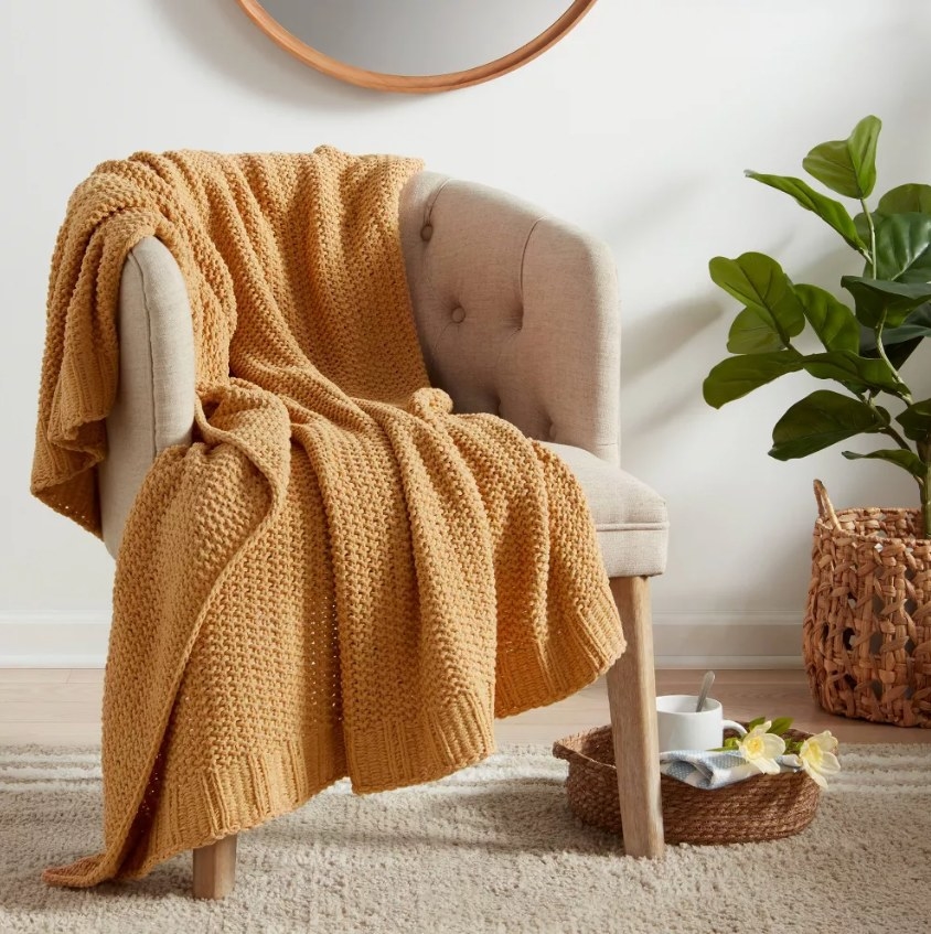A lifestyle photo of the knit throw draped over an arm chair
