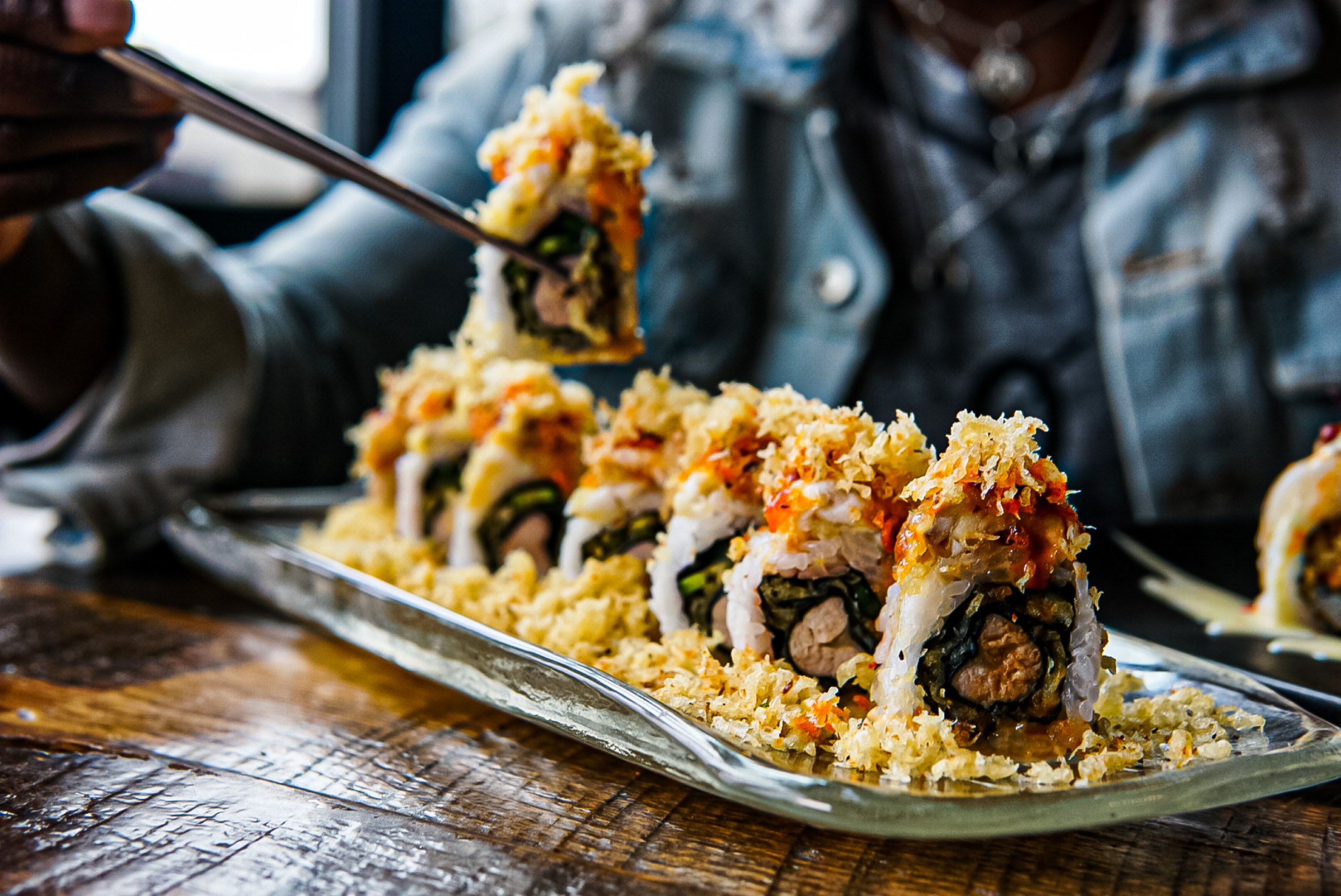 A person eating a sushi roll with chopsticks