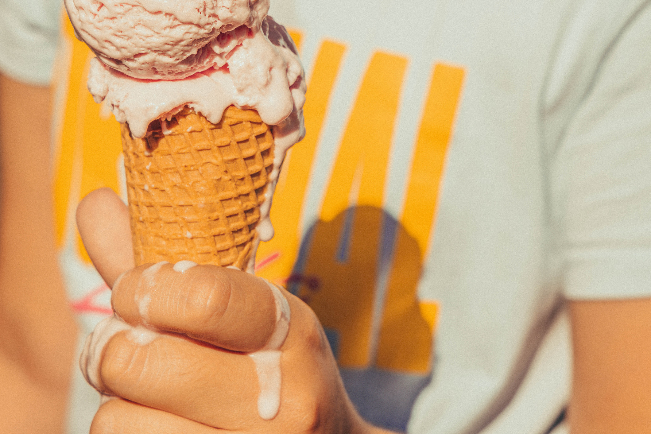A person holding ice cream cone melting in hot summer