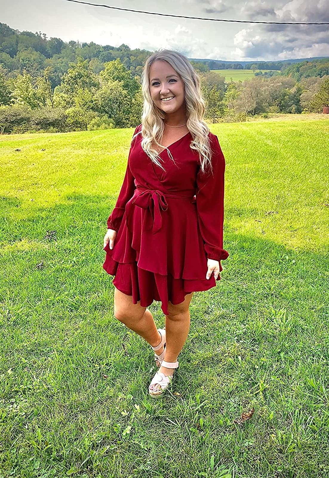 reviewer wearing long sleeve red mock wrap mini dress with white sandals