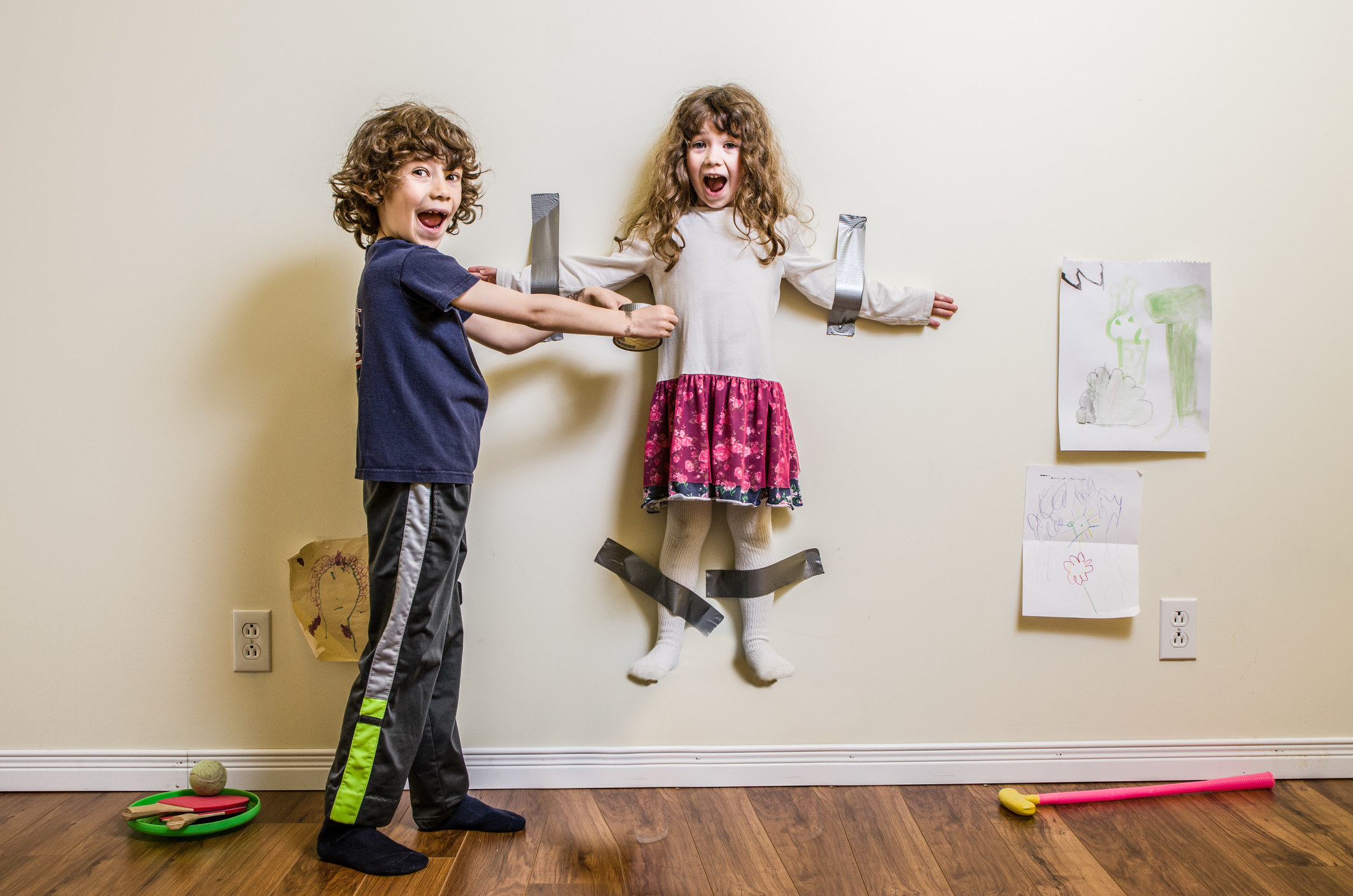 brother taping his little sister to the wall