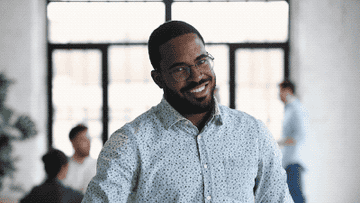 A man cheerfully points to camera