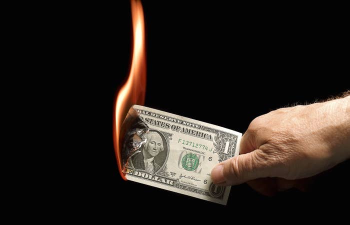 Someone burning a $1 bill