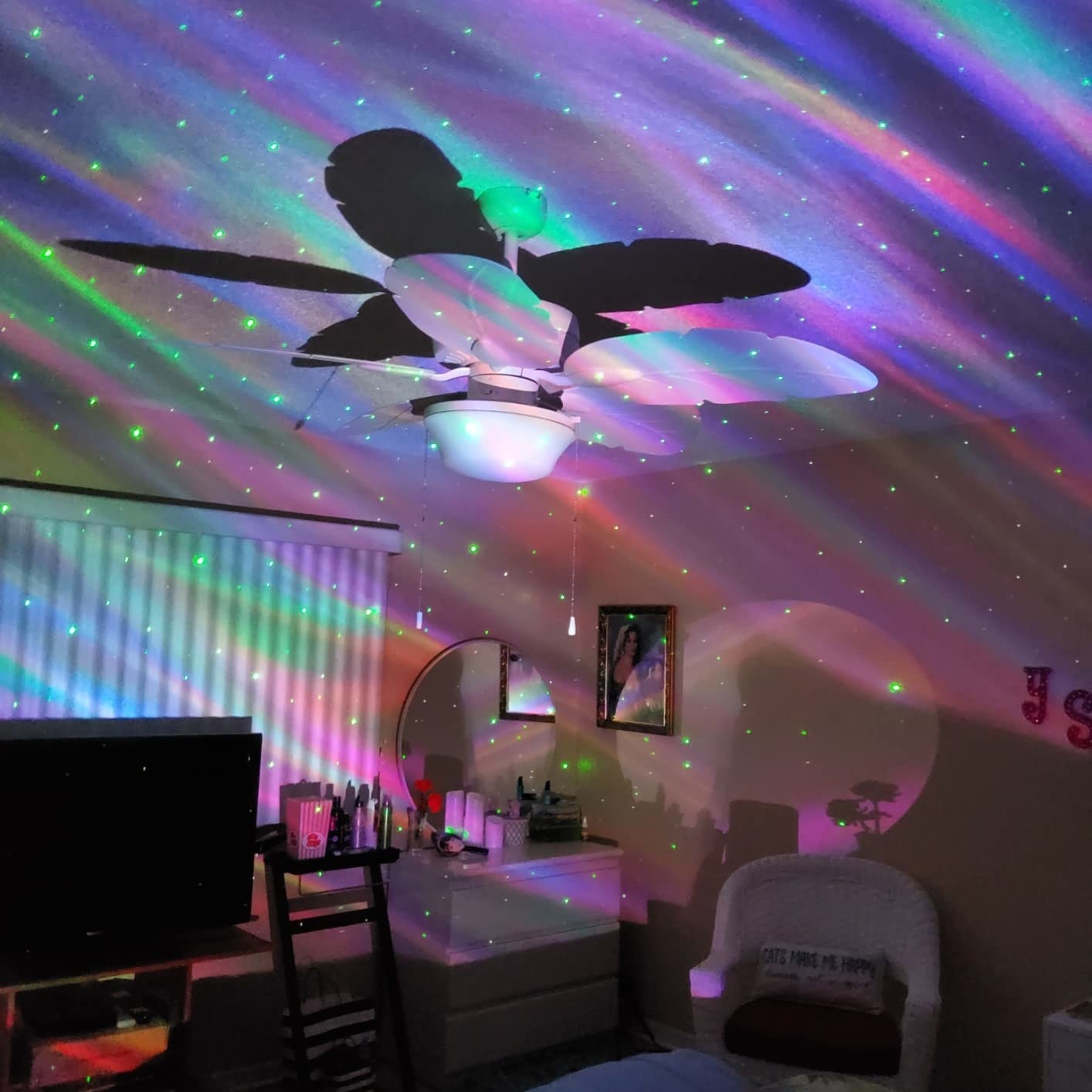 the galaxy light shining blue, purple, pink, and green lighting across a room with little stars