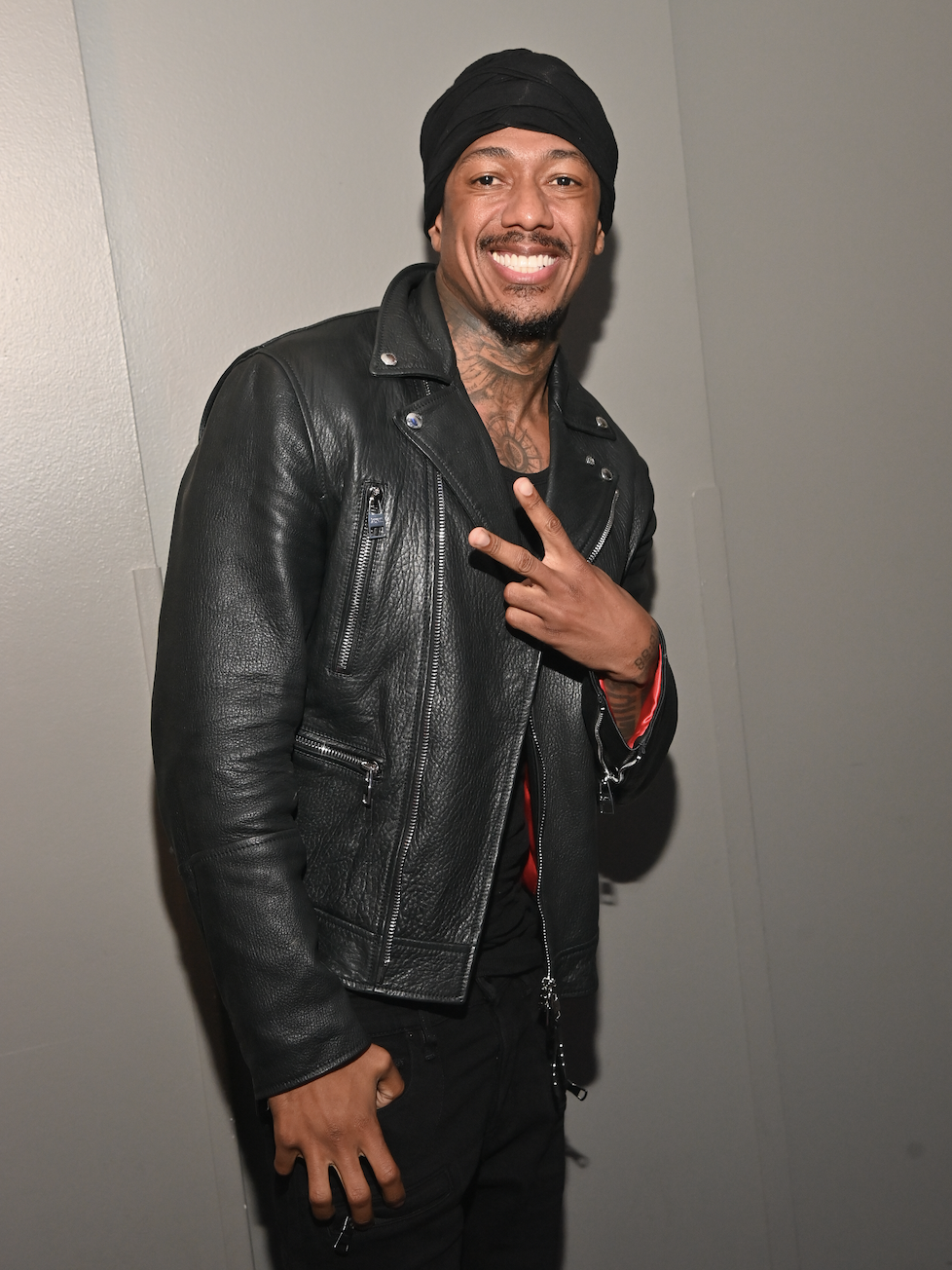 Closeup of Nick Cannon giving the peace sign and smiling