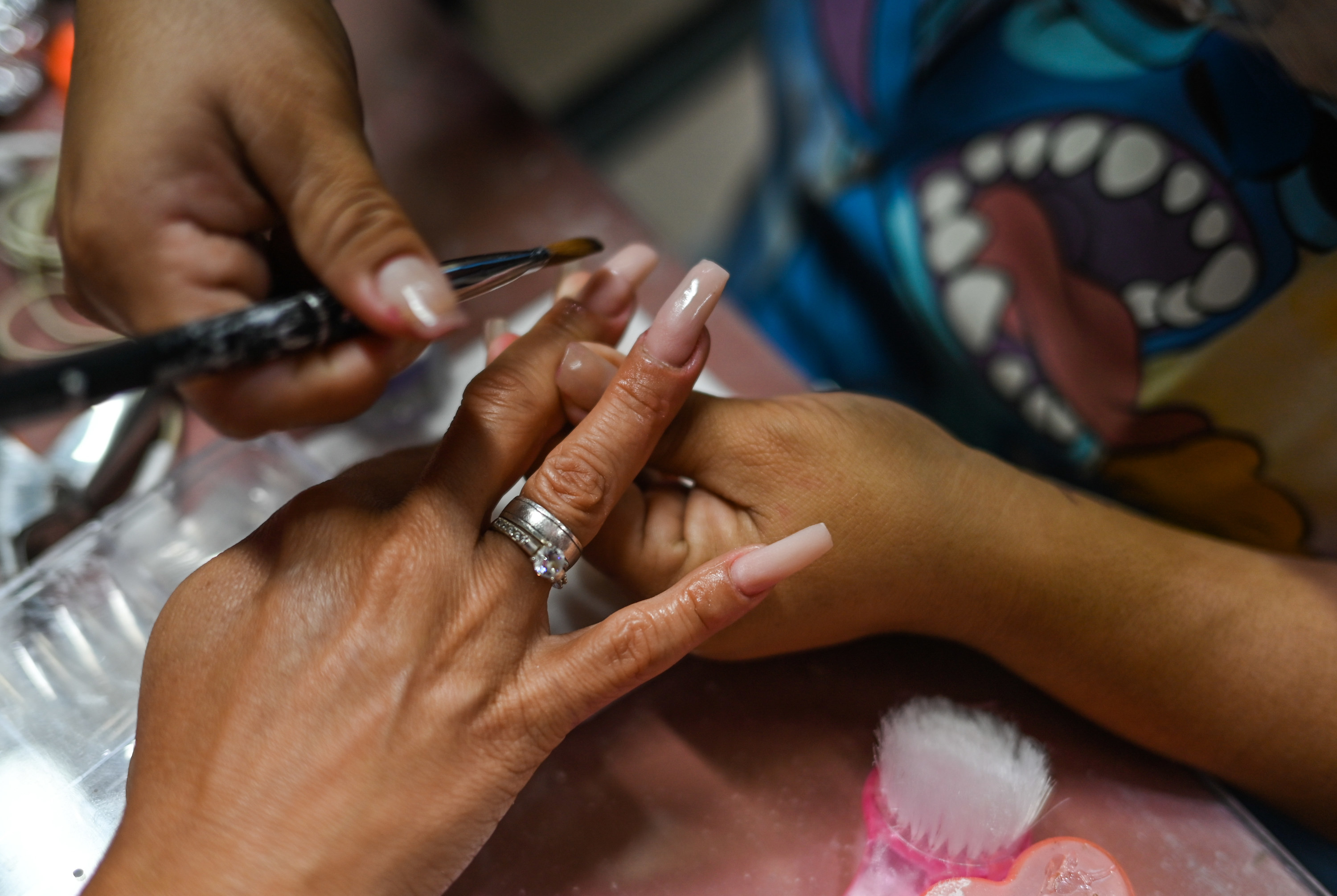 a manicurist painting a long nail in a nail salon