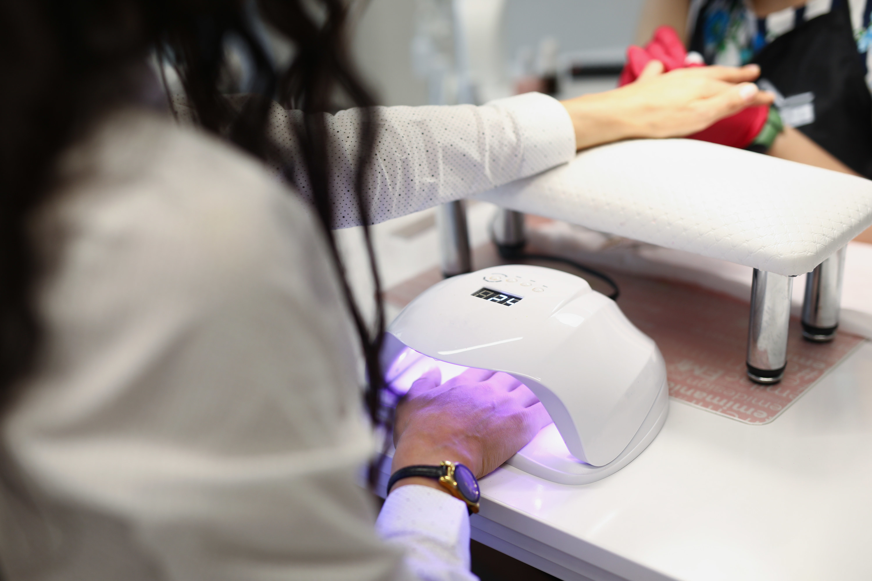 Close-up of manicurist covering nails of client with UV light