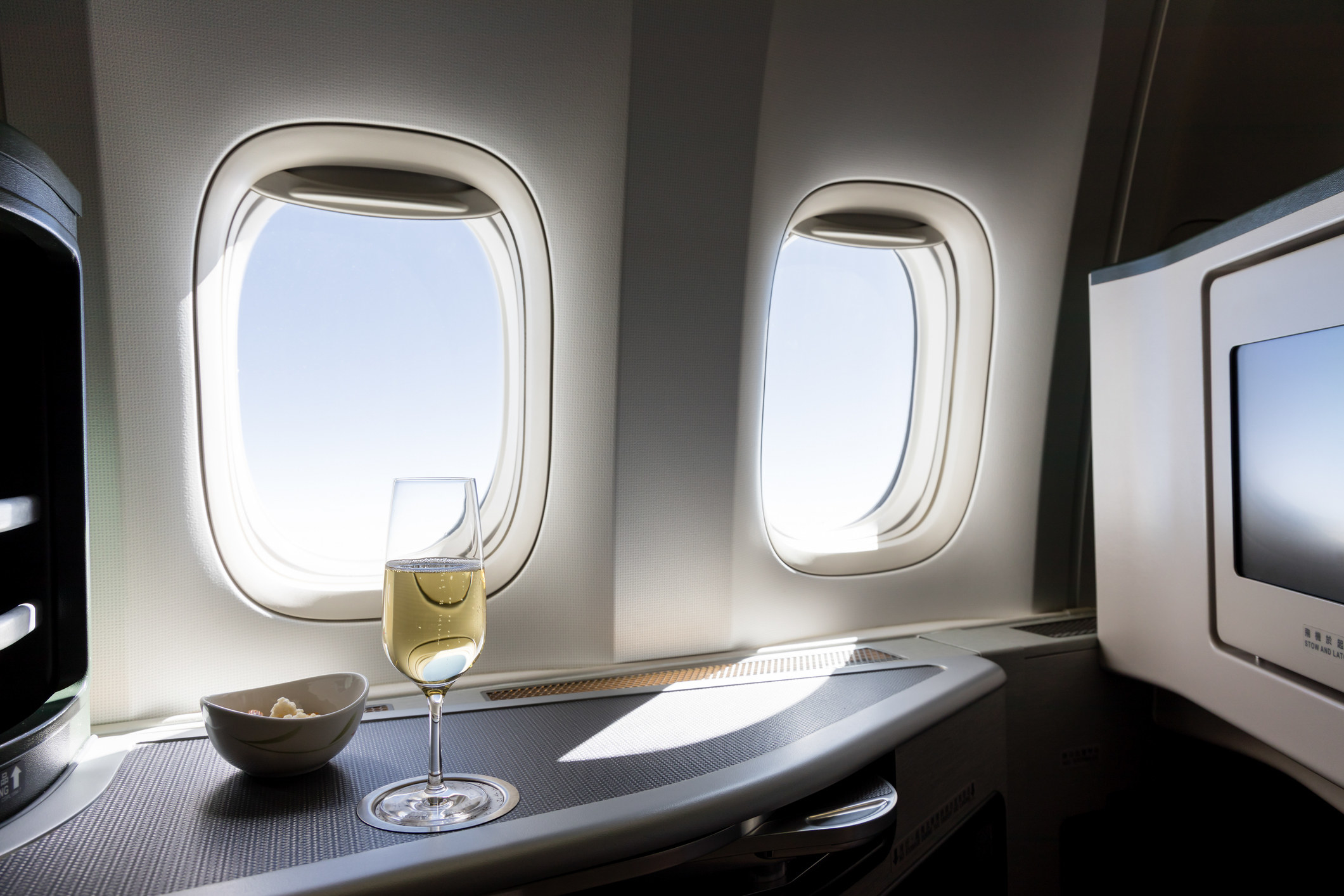 airplane windows with a glass of champagne on the tray table