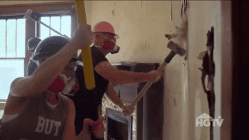 People smashing a wall with sledgehammers